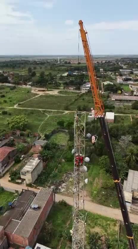 Operação de içamento de estrutura com guindaste em área rural